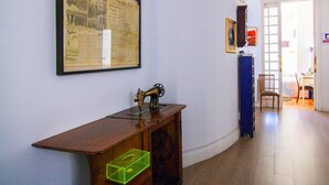 Ein Zimmer mit einem gerahmten Zeitungsartikel an der Wand, einer alten Nähmaschine auf einem Holztisch und einem blauen Schrank.