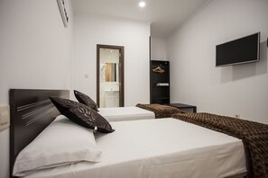 A hotel room with two beds, a TV, a wardrobe, and a bathroom visible through an open door. - Hostal Rincón de Sol - Centro Madrid - Self Checkin (Madrid)