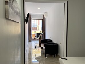 Habitación triple Deluxe, 3 camas individuales, baño privado | Área de sala de estar | Televisión de pantalla plana 