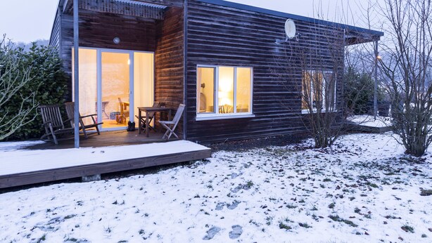 A modern wooden house with a covered porch, large windows, and a snow-covered yard. - EIFELTRAUM Mediterrana - pure silence (Berlingen)