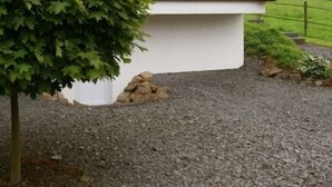 A modern house with a wooden exterior, a white base, and a gravel driveway. - EIFELTRAUM Mediterrana - pure silence (Berlingen)