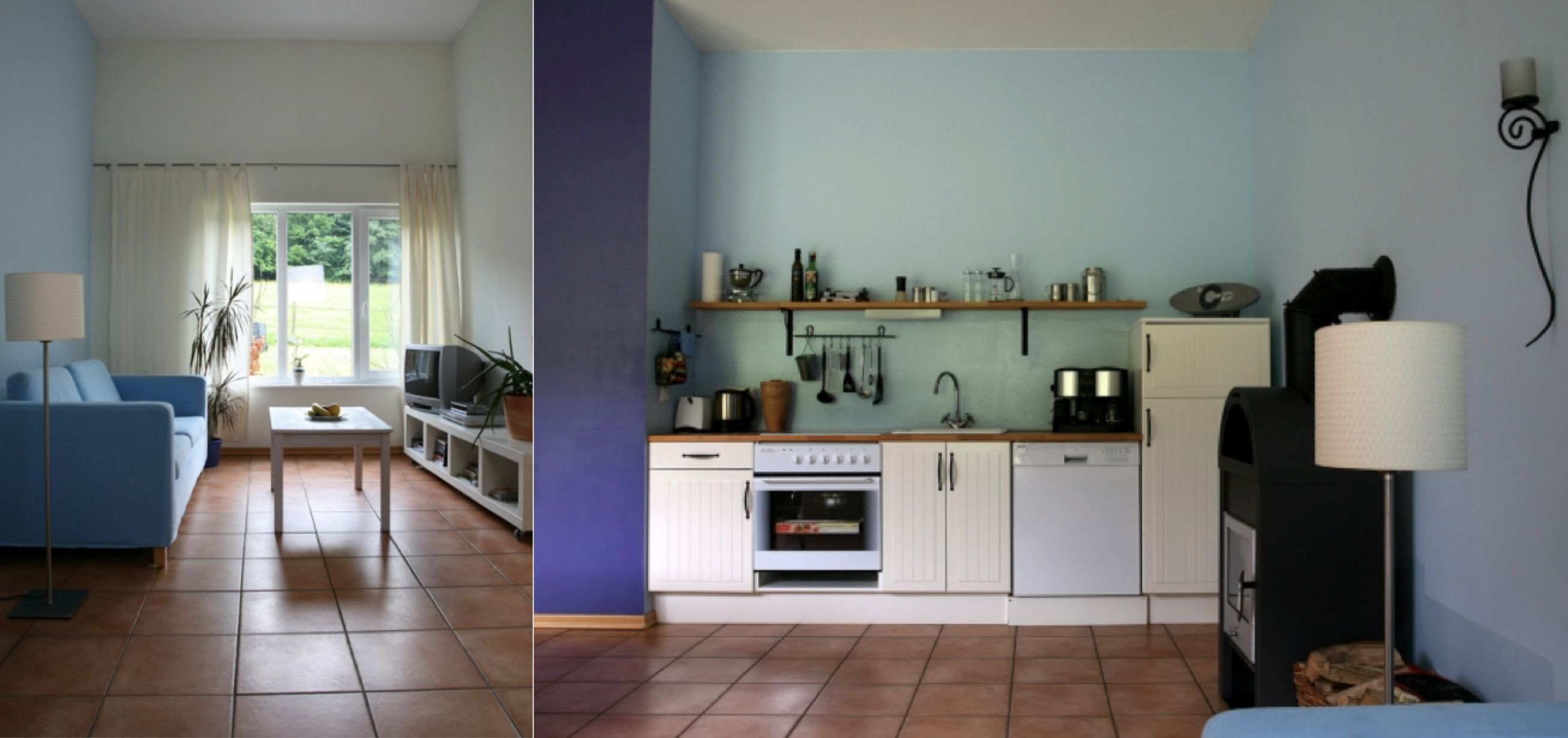 A living room with a blue sofa, a small table, and a TV. The kitchen has white cabinets, a stove, and a microwave.