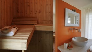 Un sauna en bois avec un banc et des serviettes, et une salle de bain avec un mur orange, un lavabo et un miroir.