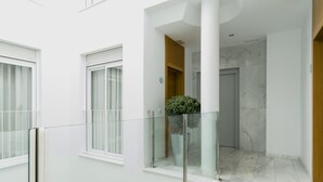 A modern interior with a glass balustrade, white walls, and a marble floor. - Suites del Pintor Historial Center, by Hoteles con Cultura (Málaga)