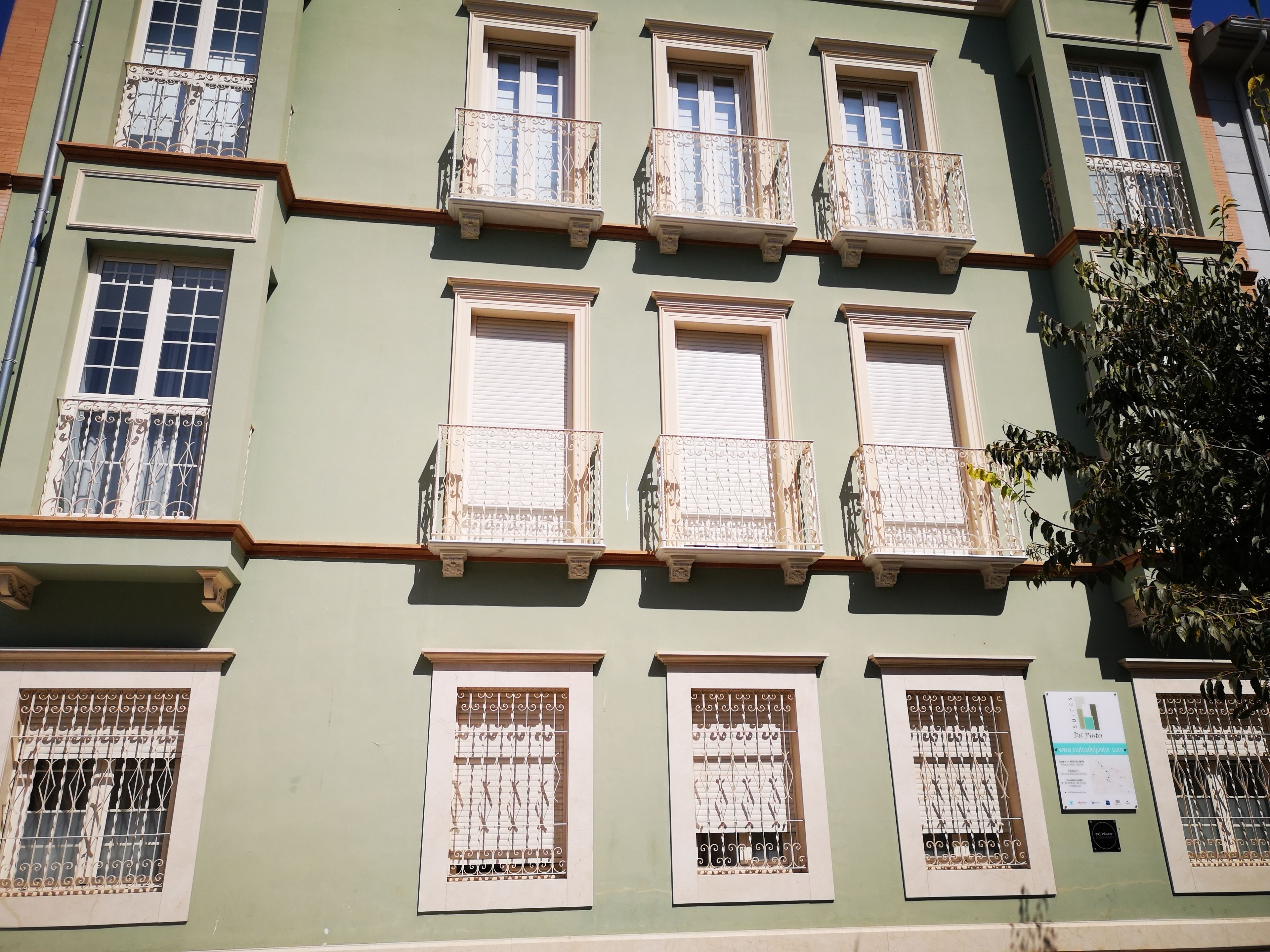 Un immeuble à plusieurs étages doté de balcons, de fenêtres ornées de grilles en fer forgé décoratives et d’une enseigne indiquant que les animaux de compagnie sont les bienvenus.