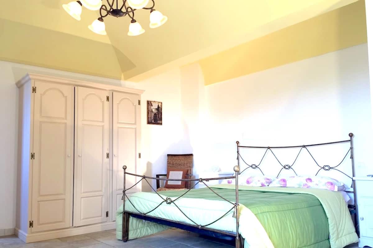 Un dormitorio con cama, armario y candelabro.