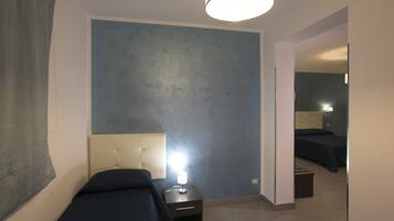 Habitación de hotel con dos camas, una mesita de noche con lámpara, un espejo y una pared de acento azul.