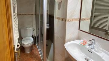 A bathroom with a toilet, shower, and sink.