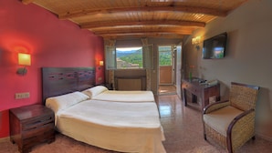 A hotel room with two beds, a wooden ceiling, a TV, and a view of the mountains. - Hotel Casa Custodio (Isabena)