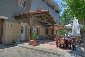An outdoor patio area with tables and chairs, a covered seating area, and a building with a tiled roof. - Hotel Casa Custodio (Isabena)