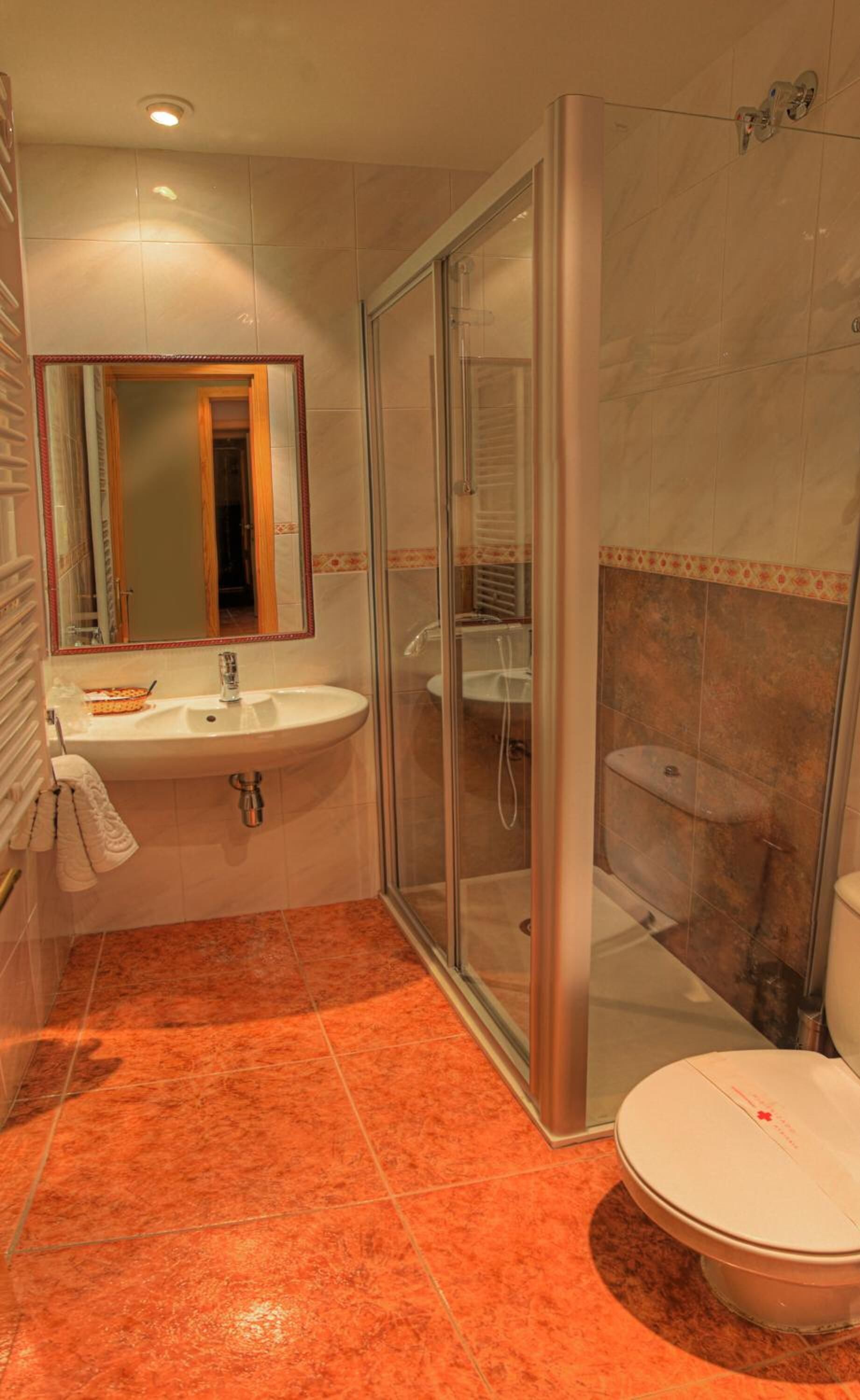 A bathroom with a glass-enclosed shower, a sink, and a toilet.