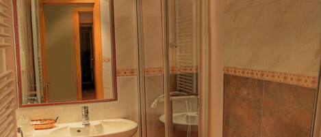 A bathroom with a glass-enclosed shower, a sink, and a toilet.