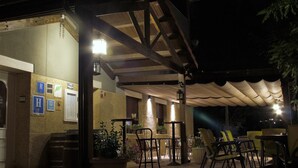An outdoor patio area with tables and chairs, a covered seating area, and a wall with posted signs. - Hotel Casa Custodio (Isabena)