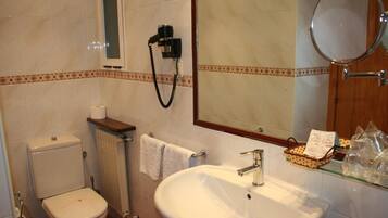 A bathroom with a toilet, sink, towel rack, and a mirror.