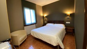 Een slaapkamer met een bed, een stoel, een raam en twee wandlampen.