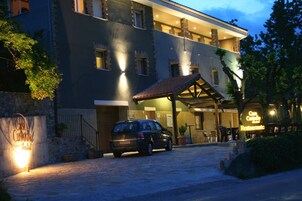 Un hotel con fachada de piedra, un vestíbulo cubierto y un coche estacionado.