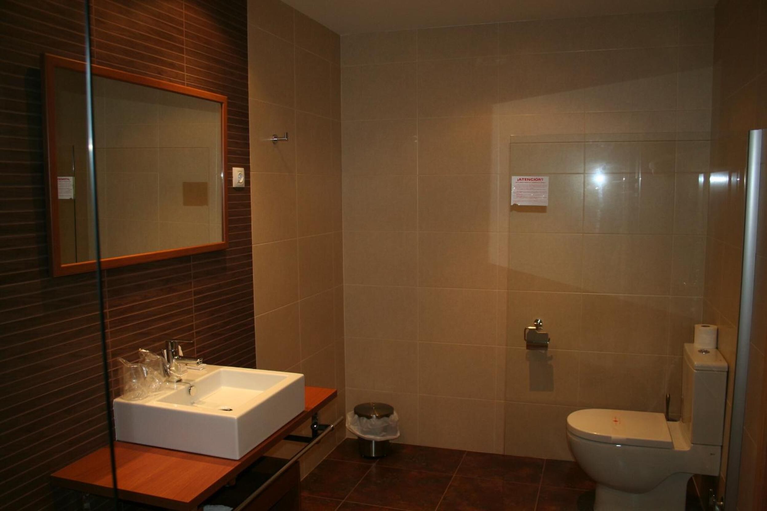 A bathroom with a white sink, mirror, and toilet.