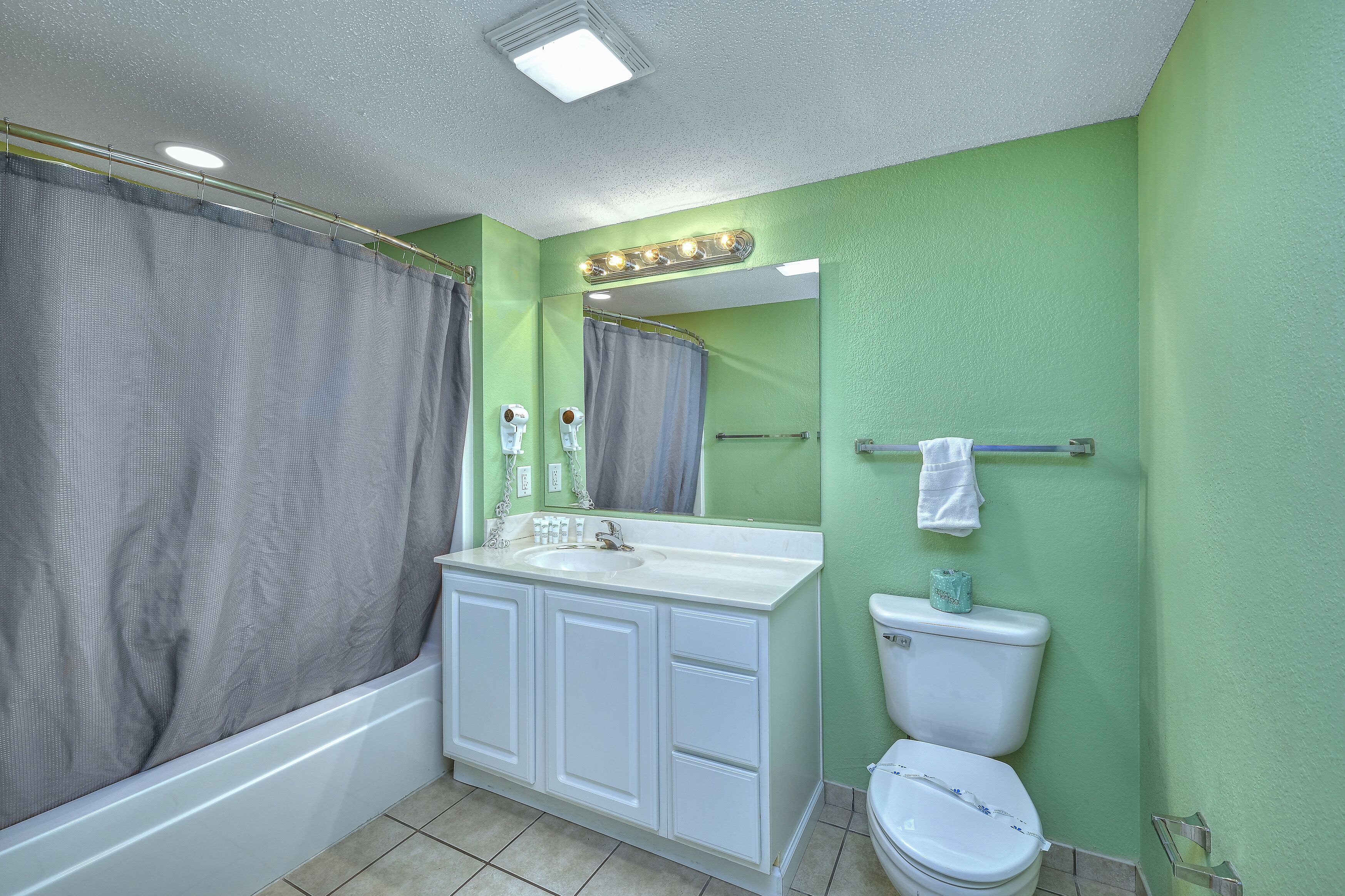 Une salle de bain avec une baignoire, un lavabo avec un miroir et des toilettes.