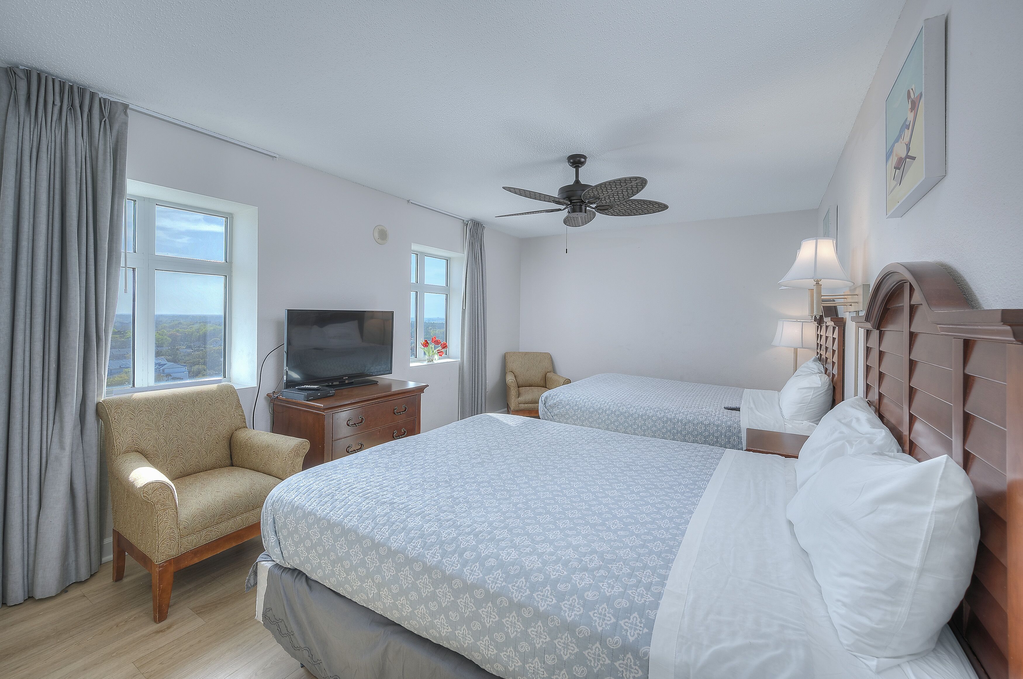 A hotel room with two beds, a television, a desk, and a chair.