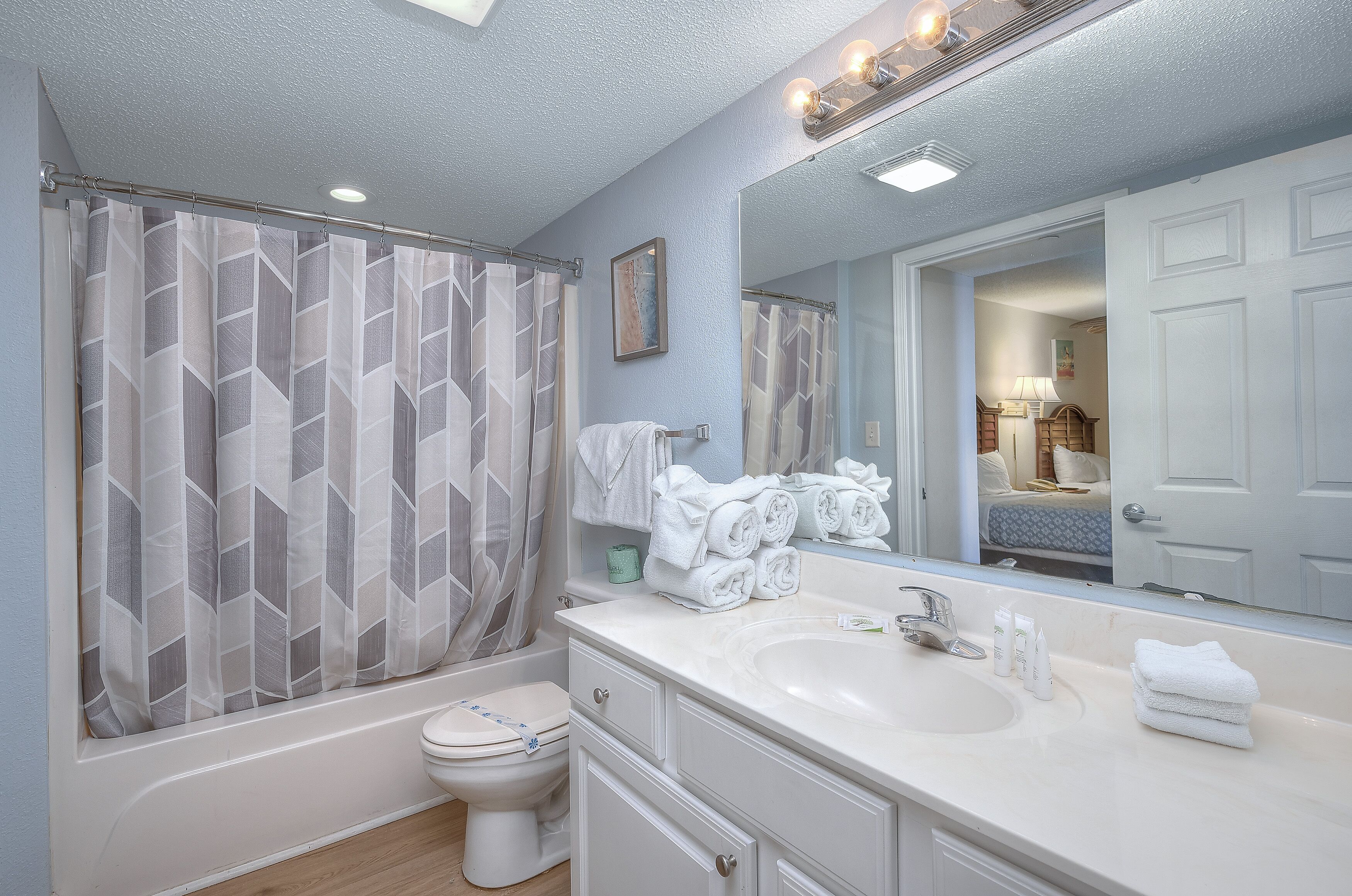 A bathroom with a bathtub, toilet, sink, and a large mirror.
