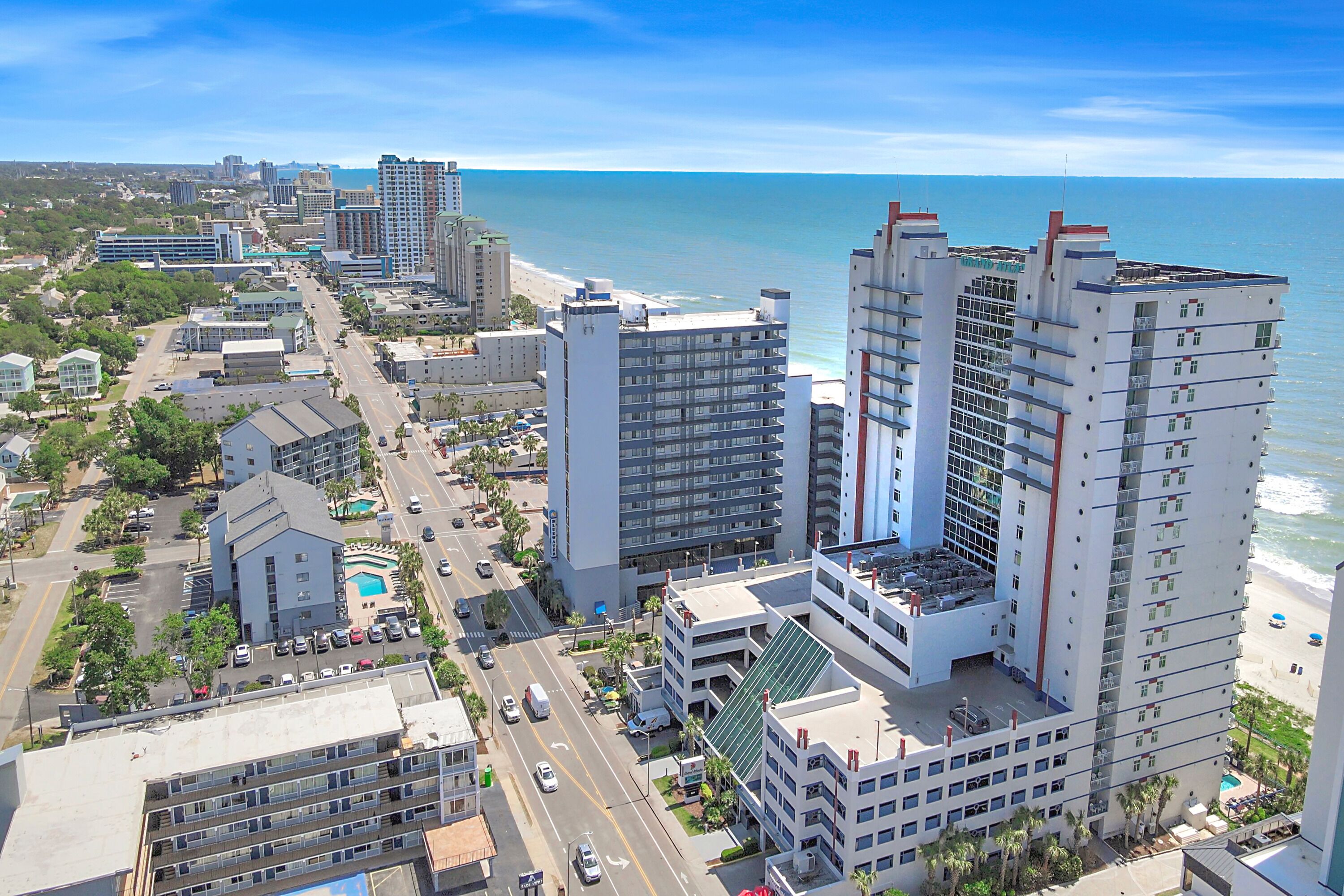 Un grand hôtel à plusieurs étages, doté d’une piscine et offrant une vue sur la plage.