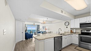 A modern kitchen with white cabinets, stainless steel appliances, and a built-in dishwasher. - Grand Atlantic by Elliott Beach Rentals (Myrtle Beach)