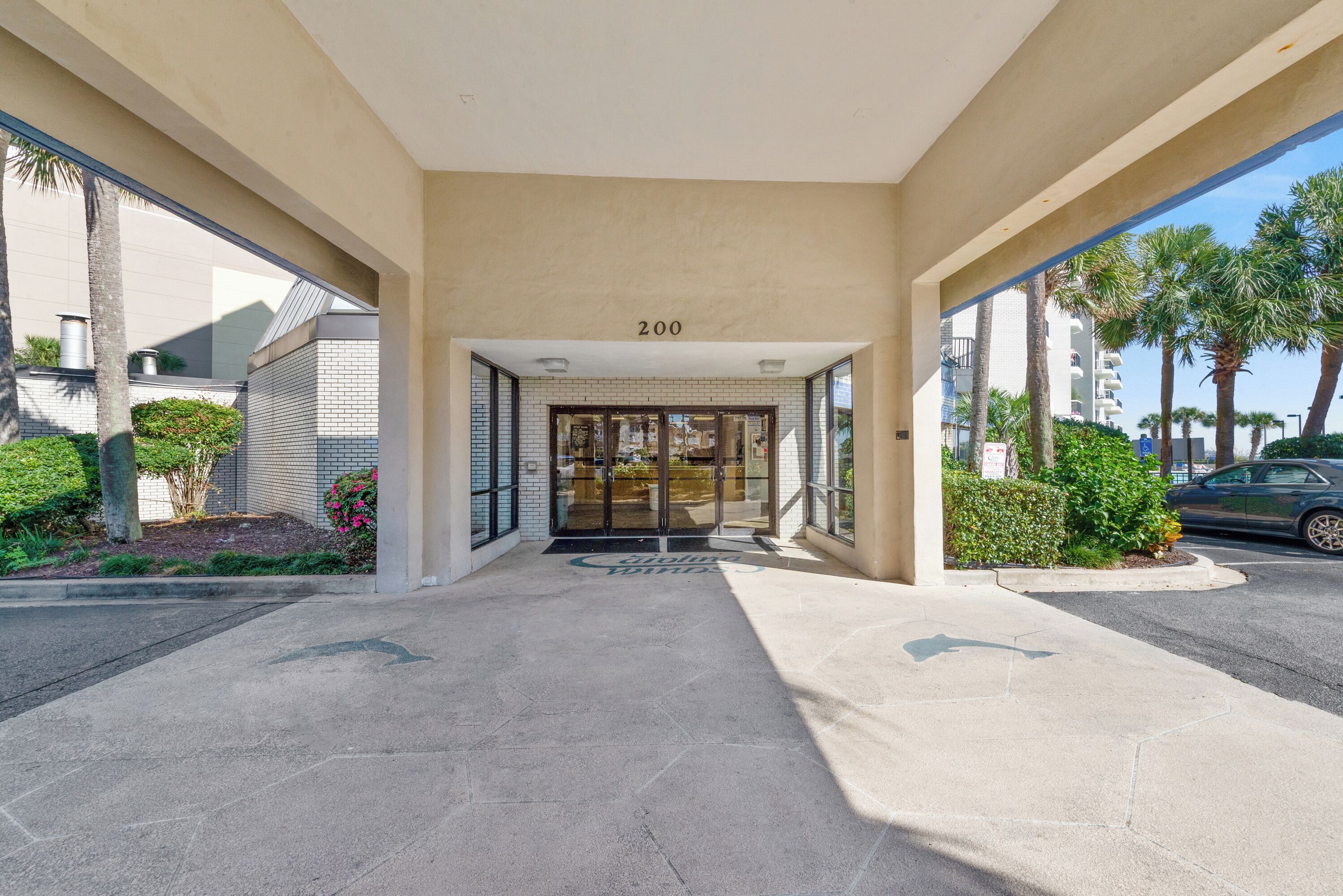 A hotel entrance with a glass door, number 200, and a paved walkway leading to it.
