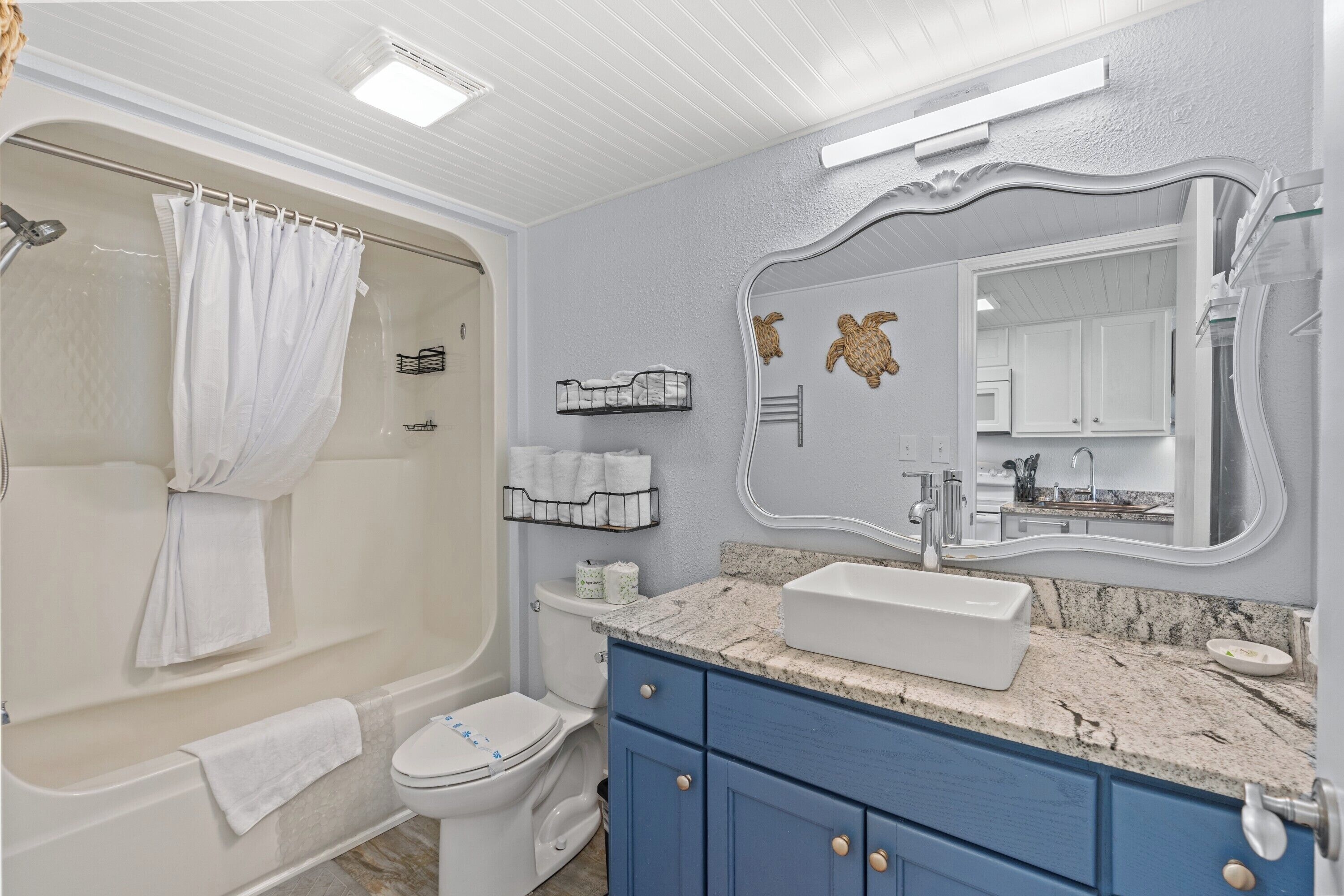 A bathroom with a bathtub, toilet, vanity with a sink, and a large mirror.