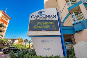 A sign for Carolinian Beach Resort with a digital display advertising a fitness center.
