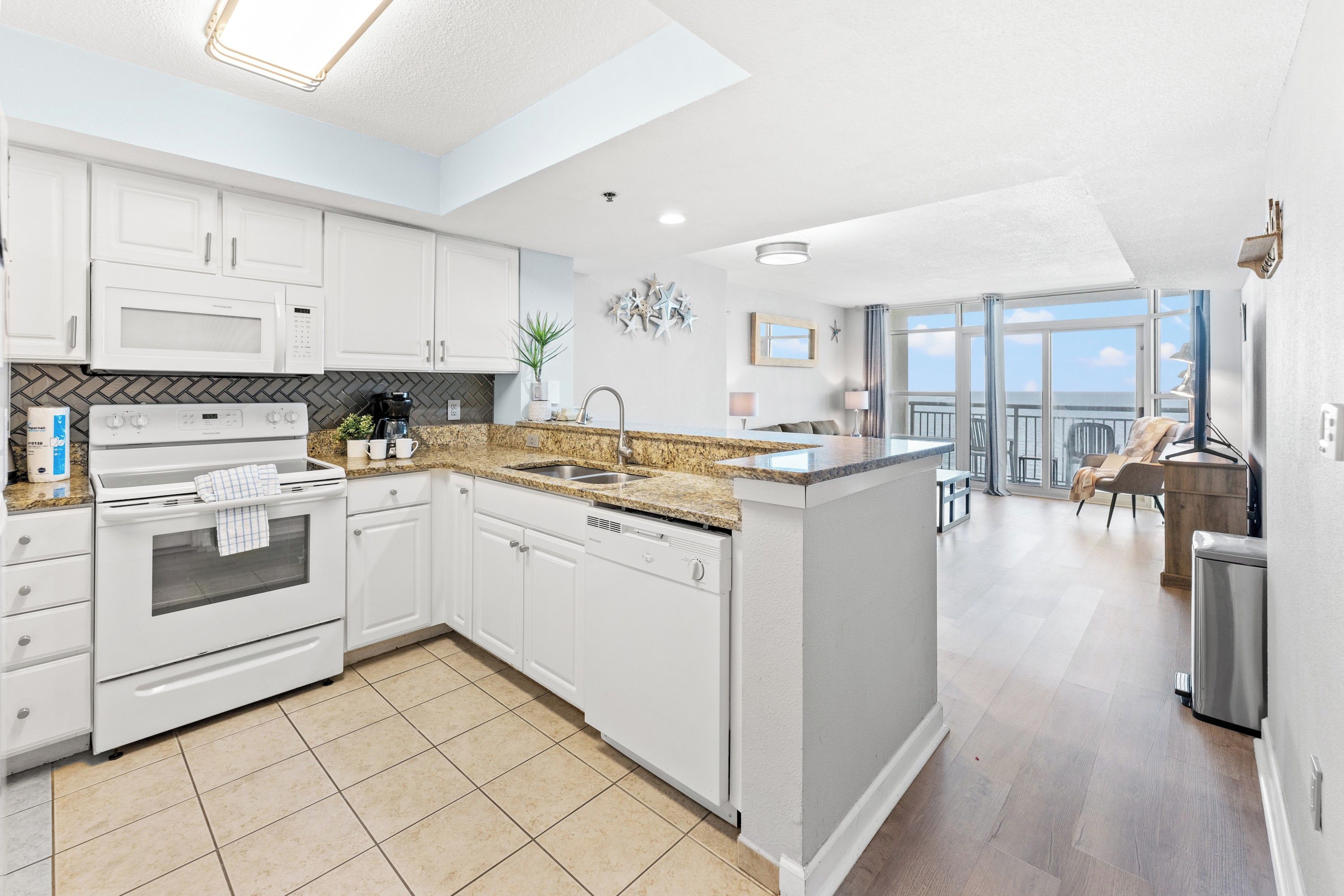 A modern kitchen with white cabinetry, a built-in oven, and a dishwasher.