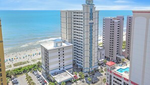 A high-rise hotel with a central tower, a pool, and a beach view. - Units at Carolinian Beach Resort by Elliott Beach Rentals (Myrtle Beach)