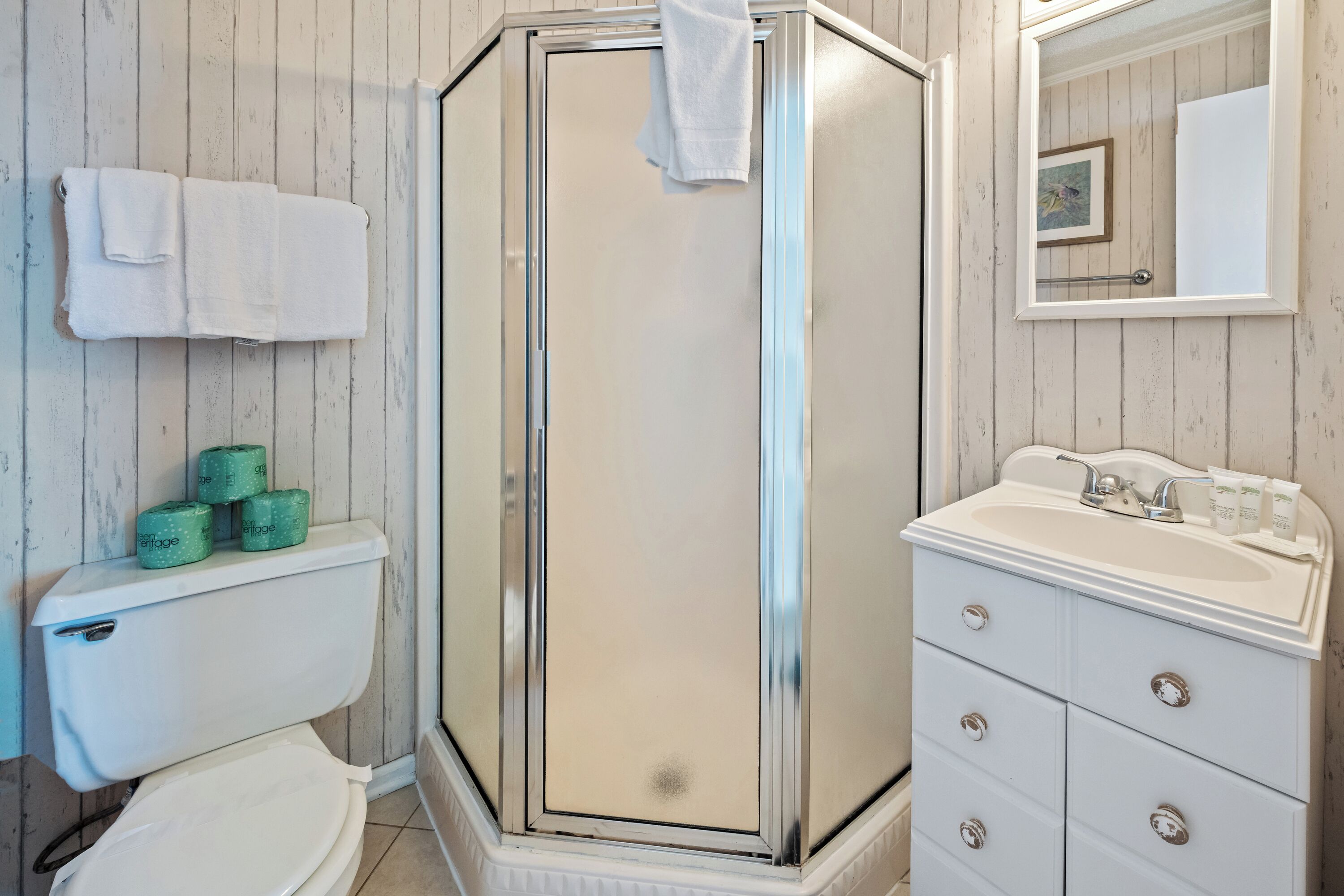 Un baño con inodoro, cabina de ducha, lavabo y espejo.