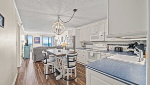 A modern kitchen with white cabinets, a blue countertop, and a chandelier.
