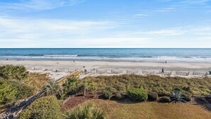 A beach with a wooden boardwalk, sandy shore, and ocean waves.