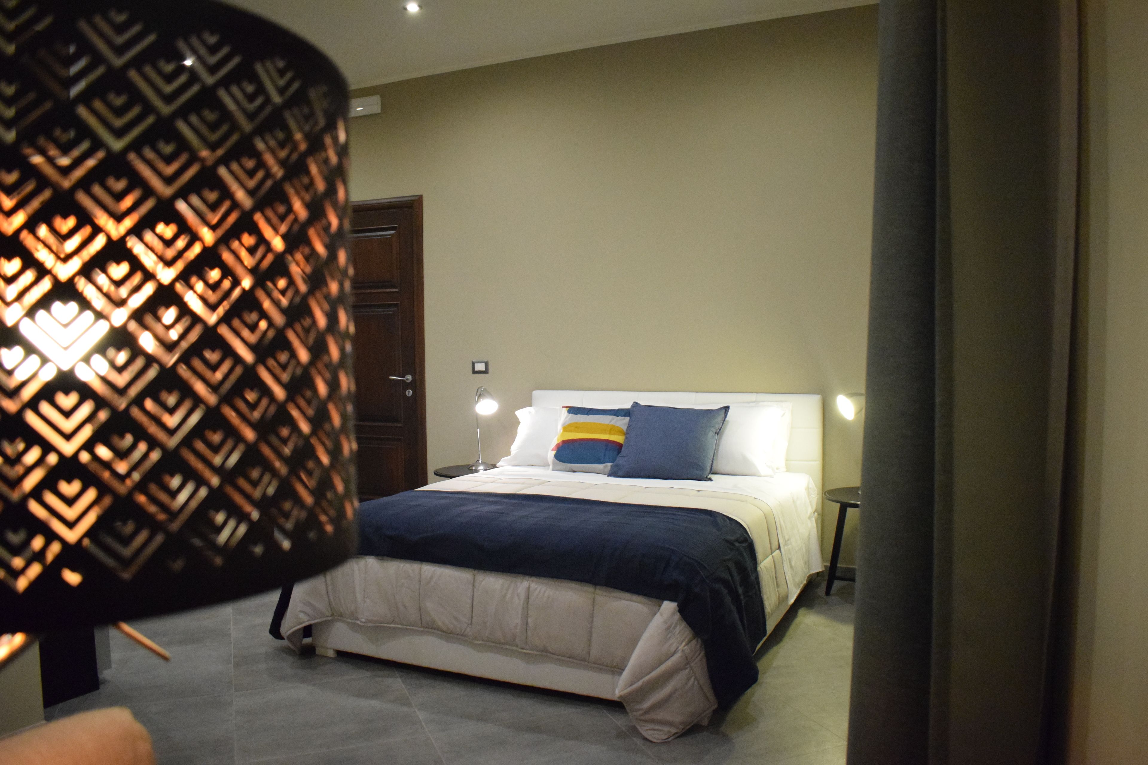 Quarto com cama, mesas de cabeceira e parede estampada.