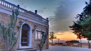 A stone building with a balcony, arched windows, and cacti. - Tenuta Bellaprima (Niscemi)
