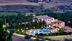 A villa with a swimming pool, surrounded by lush greenery and hills. - Tenuta Bellaprima (Niscemi)