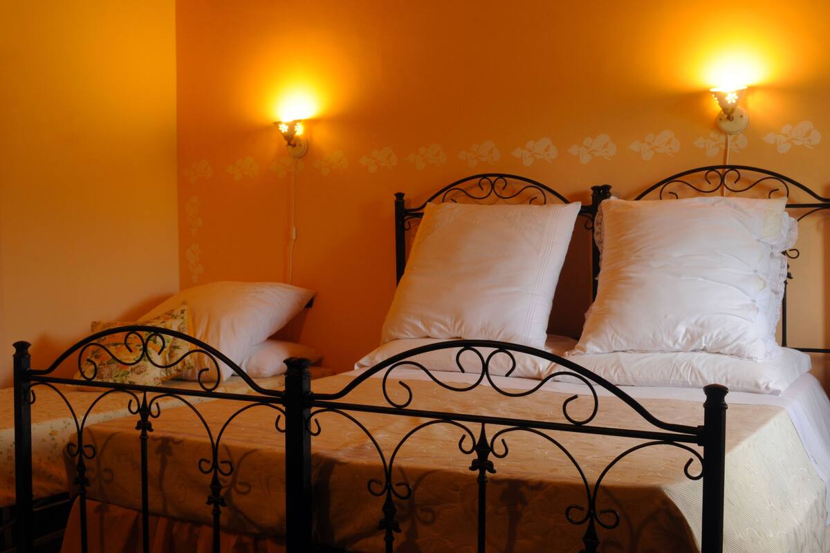 A bed with a metal frame, white bedding, and two wall-mounted light fixtures.