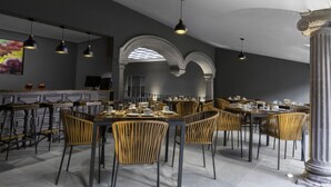 Un espace de restauration moderne doté de hauts plafonds, de fenêtres en arc de cercle et d’un mélange de sièges de bar et de tables.