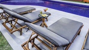 Un espace aménagé au bord de la piscine, avec des chaises longues et une table où sont servis des boissons et des citrons.