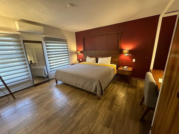 A hotel room with a bed, bedside tables, a desk, and a chair.