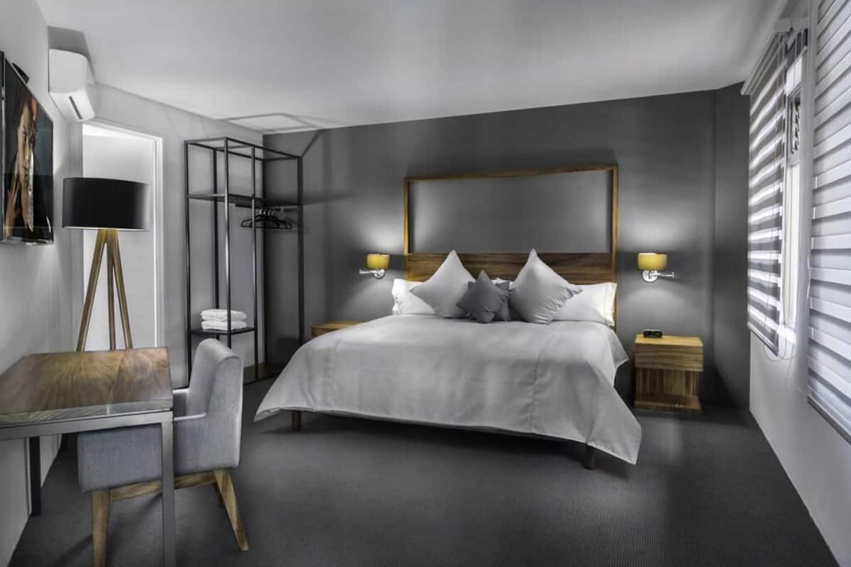 Una habitación de hotel moderna con una cama grande, mesitas de noche, un escritorio y una silla.
