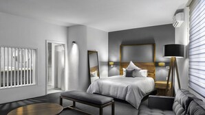 Une chambre d’hôtel moderne comprenant un lit, une banquette, une petite table et un canapé.
