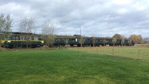 A train passing through a grassy area with trees and a cloudy sky. - Sint-Amands Country Escape (Sint Amands)