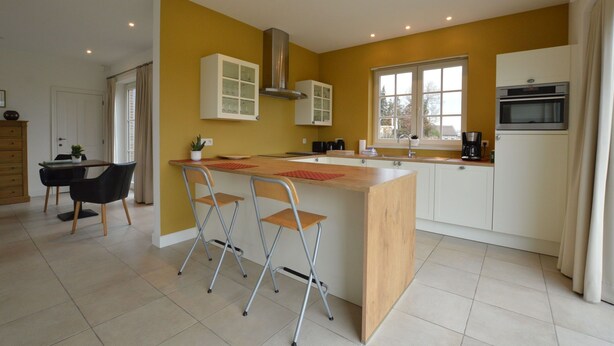 A modern kitchen with a central island, white cabinets, and a stainless steel range hood. - Sint-Amands Country Escape (Sint Amands)