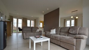 A spacious living room with a beige sofa, a white coffee table, and a large window with curtains. - Sint-Amands Country Escape (Sint Amands)