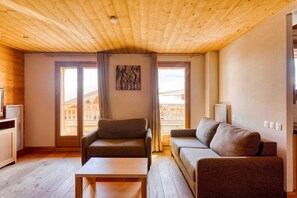 Quarto com teto de madeira, dois sofás, uma mesinha e um radiador.