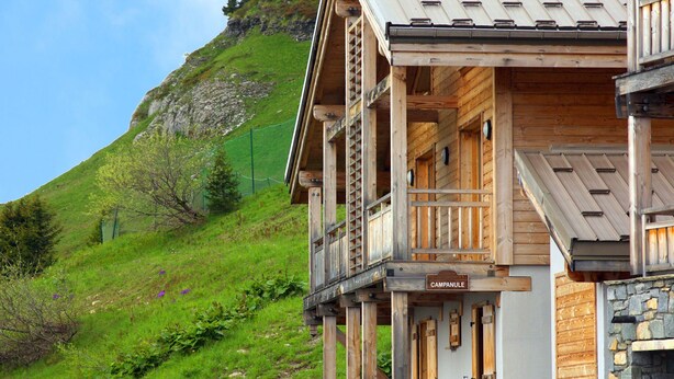 A wooden chalet with a balcony, a stone wall, and a sign that reads "CAMPNULE". - Grand Massif Family Retreat (Arâches-La-Frasse)
