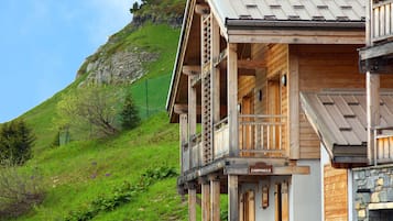 A wooden chalet with a balcony, a stone wall, and a sign that reads "CAMPNULE".