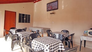 Un comedor con manteles a cuadros, sillas de plástico y un televisor en la pared.